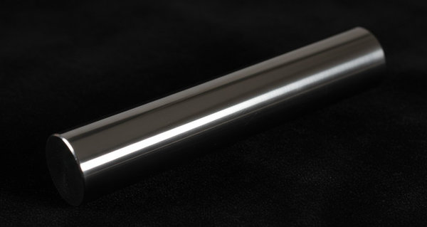 Zone-refined germanium crystal cylinder resting on dark velvet surface with dramatic studio lighting