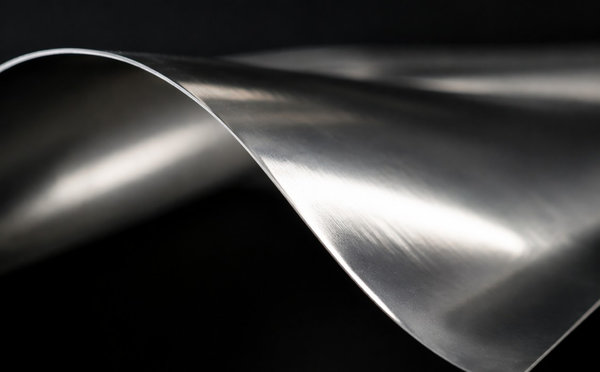 Macro view of ultra-thin flexible stainless steel foil curling at the edge