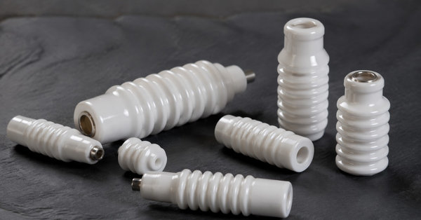 Glazed white alumina ceramic insulators arranged on a dark slate surface