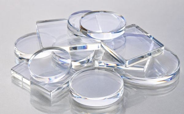 A stack of clear polished sapphire optical windows on a light surface