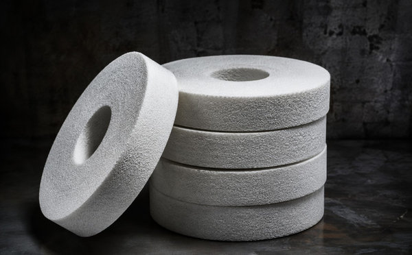 Stacked white fused alumina grinding wheels on a dark background