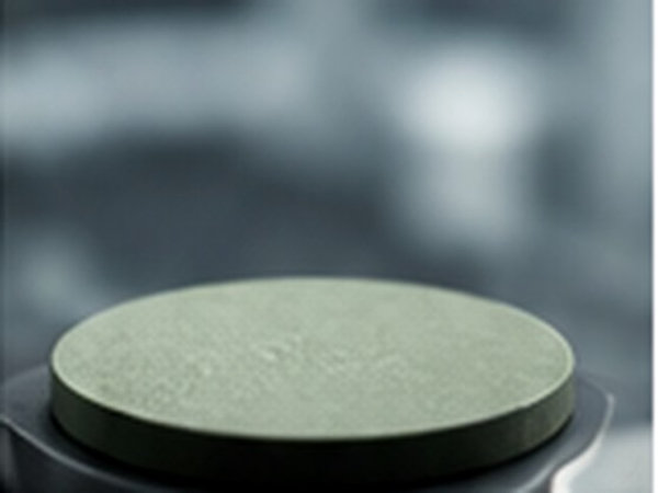Dense circular perovskite ceramic pellet positioned on a laboratory sample stage.