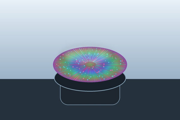 An iridescent coated wafer rests on a spin-coating platform with radial film patterns.