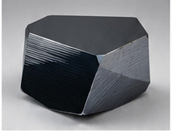 Dark faceted monocrystalline silicon block with sharply defined cut faces.
