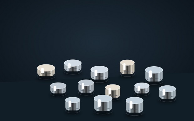 Uniform metallic alloy pellets displayed on a dark surface for evaporation-source preparation.