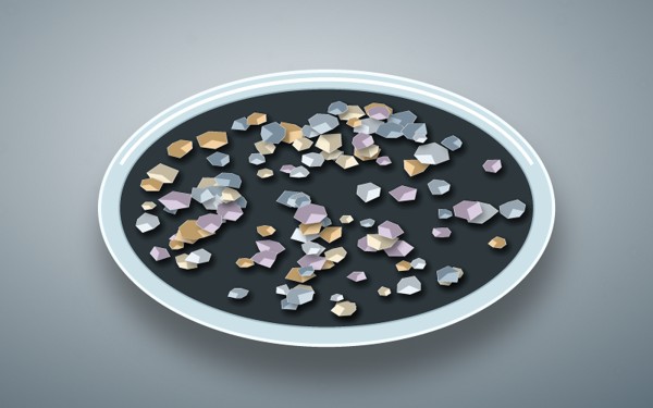 Faceted multicolor alloy granules arranged in a shallow laboratory dish.